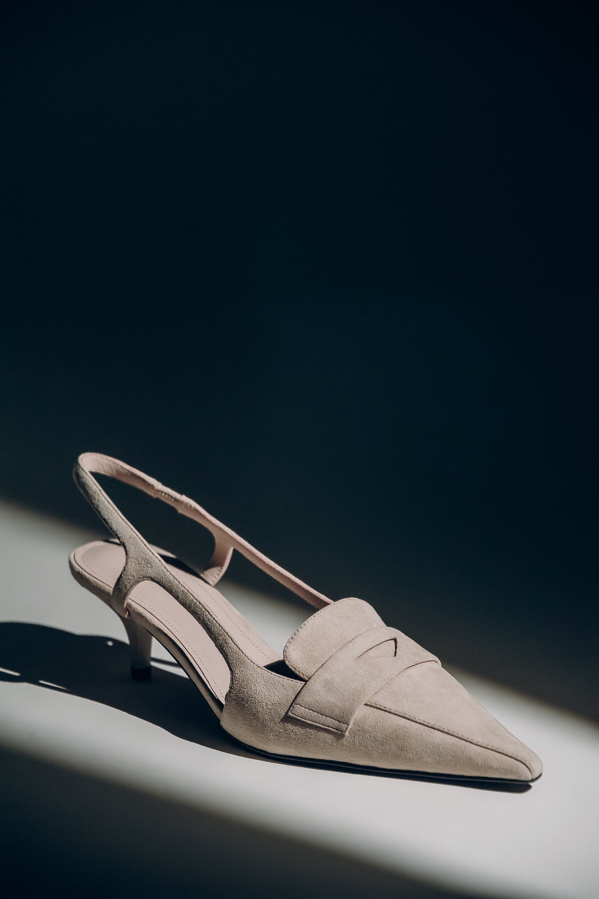 Beige Damen-Slingpumps aus echtem Velours in künstlerischer Ansicht auf dunklem Hintergrund
