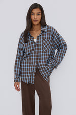 Nahaufnahme des Models in der lässig geöffneten blau-braun karierten Oversize-Hemdbluse