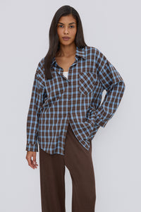 Nahaufnahme des Models in der lässig geöffneten blau-braun karierten Oversize-Hemdbluse
