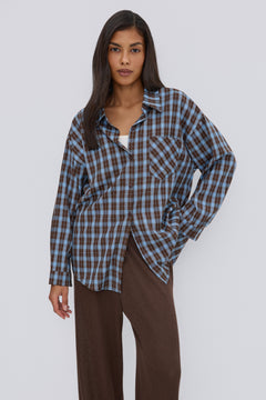 Nahaufnahme des Models in der lässig geöffneten blau-braun karierten Oversize-Hemdbluse
