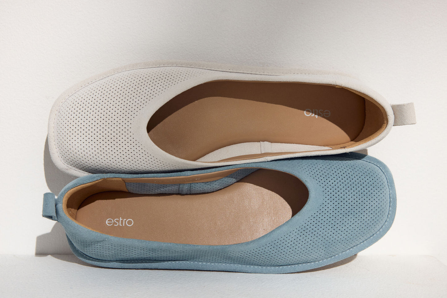 Draufsicht auf zwei Estro Damen-Ballerinas aus weichem, perforiertem Veloursleder in den Farben Hellbeige und Blau