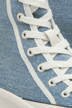 Detailaufnahme der weißen Schnürung und der textilen Struktur des blauen Sneakers