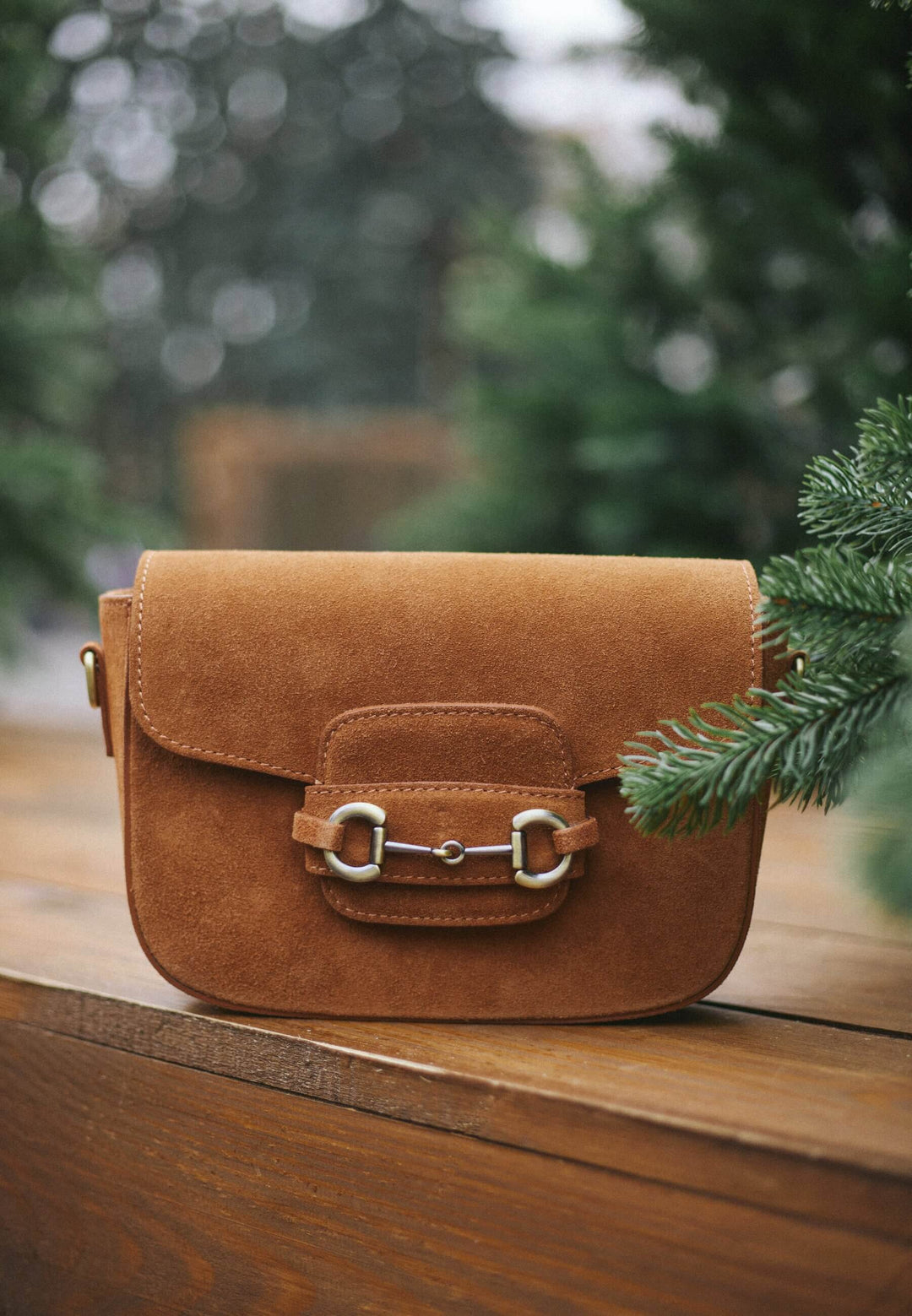 Lifestyle-Aufnahme der braunen Handtasche, platziert auf einer Holzoberfläche im Freien