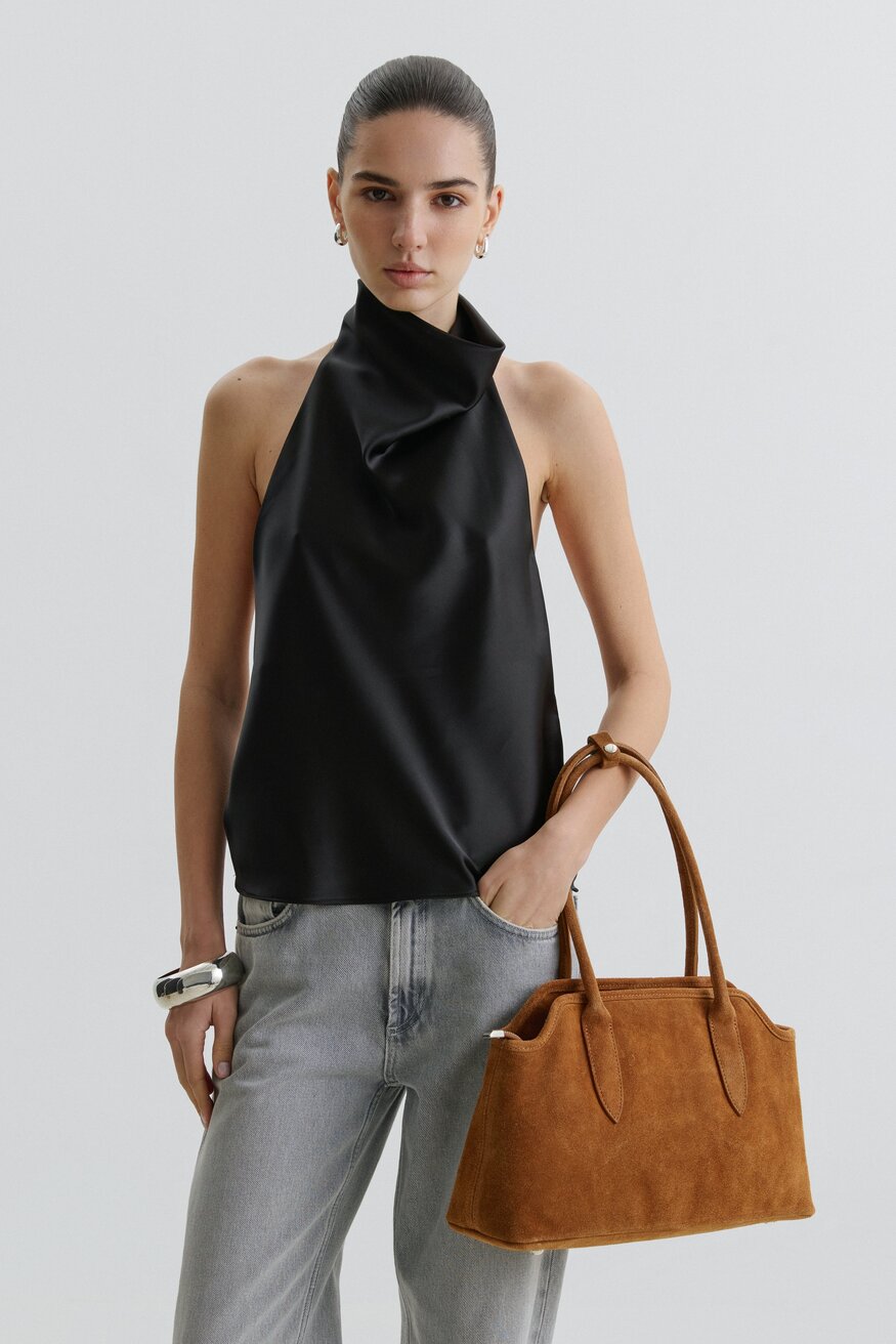 Lifestyle-Aufnahme einer Frau, die die braune Velours-Schultertasche elegant wahlweise in der Hand präsentiert