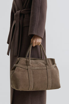 Model trägt die dunkelbeige Velours-Tote-Bag am kurzen Griff in der Hand