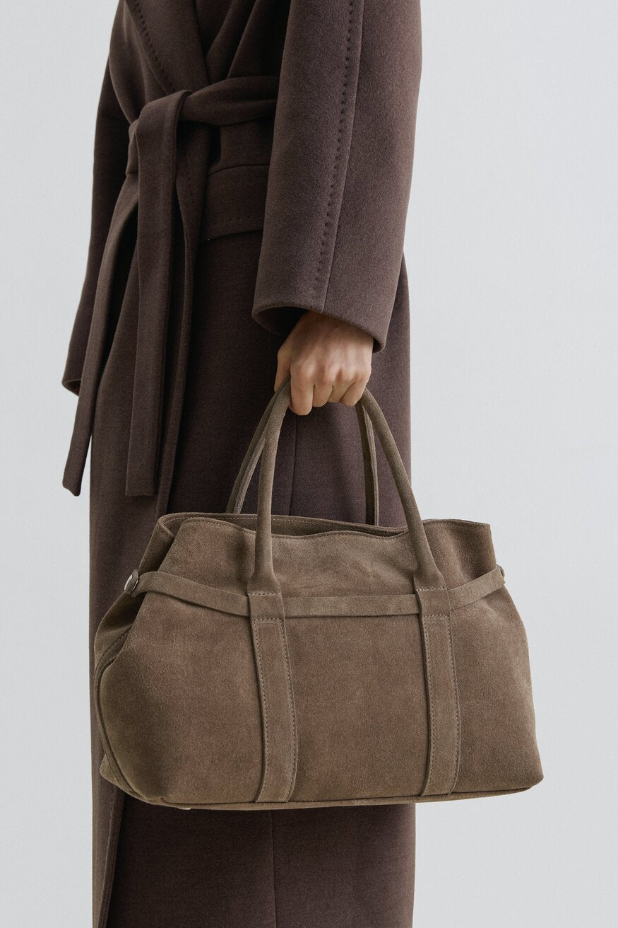 Model trägt die dunkelbeige Velours-Tote-Bag am kurzen Griff in der Hand