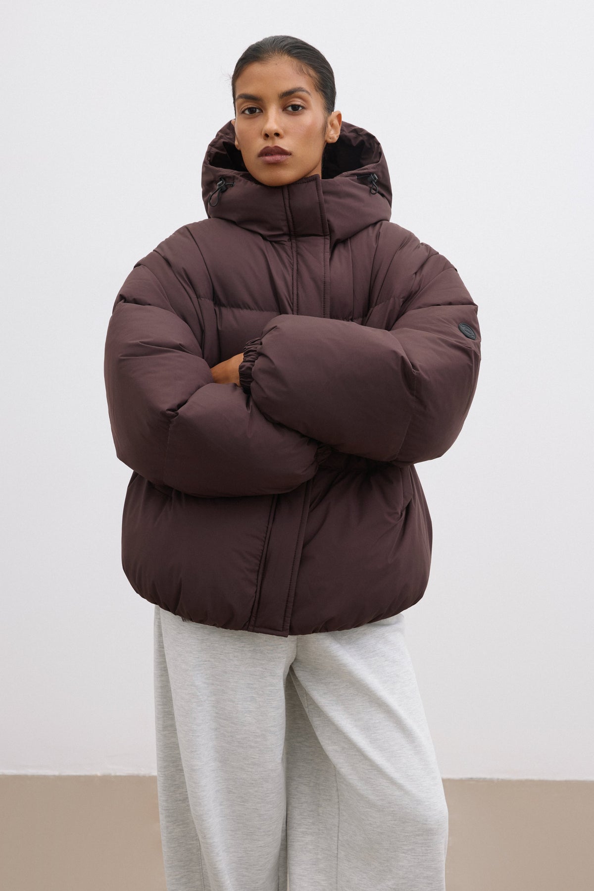Model in der geschlossenen dunkelbraunen Oversize-Winterjacke mit voluminöser Steppung 