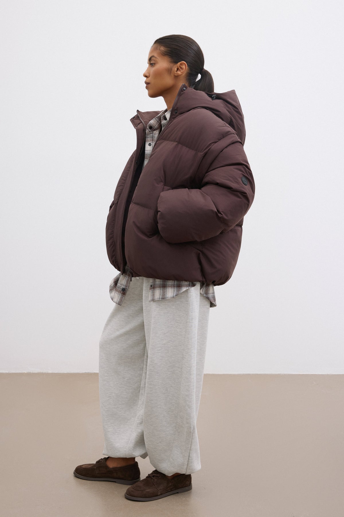 Seitenansicht der dunkelbraunen Winterjacke, die die legere Passform und die tiefen Taschen hervorhebt 