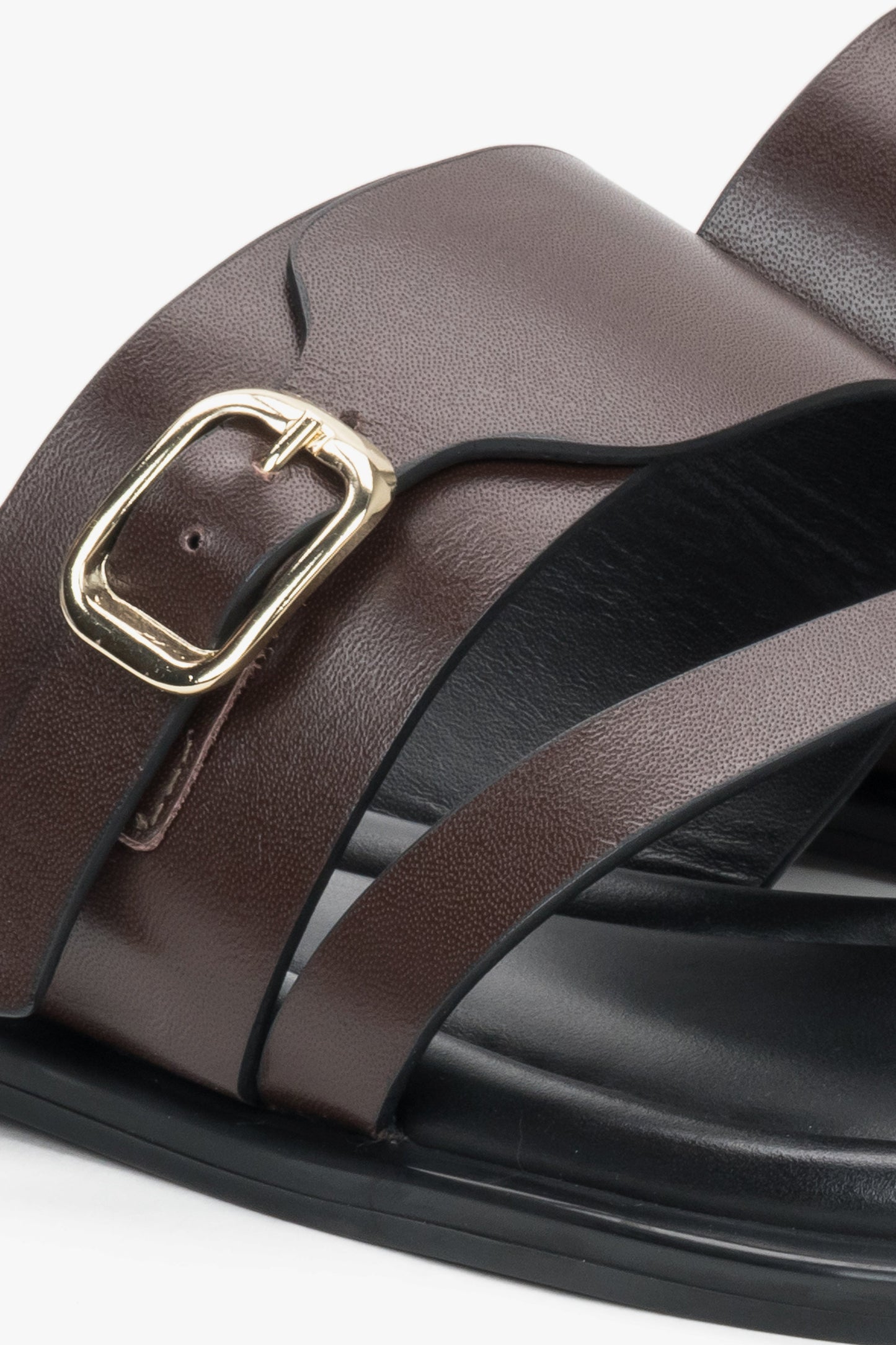 Detailaufnahme dunkelbrauner Damen-Pantoletten mit goldfarbener Schnalle und Zehenschlaufe