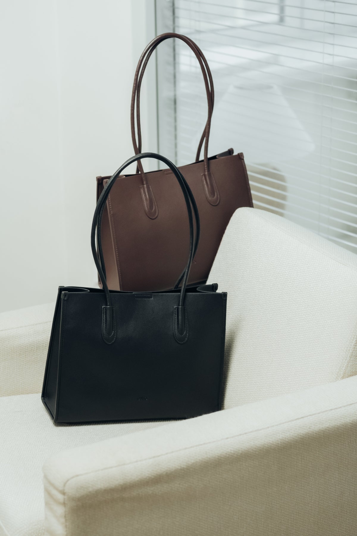 Schwarze und dunkelbraune Damen-Handtasche aus Echtleder nebeneinander im eleganten Studio-Setting