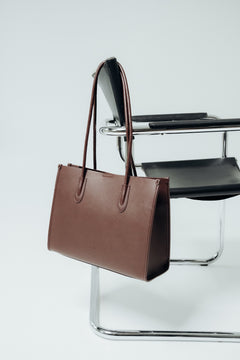 Seitliches Profil der dunkelbraunen Damen-Shopper-Tasche aus Echtleder am Designerstuhl