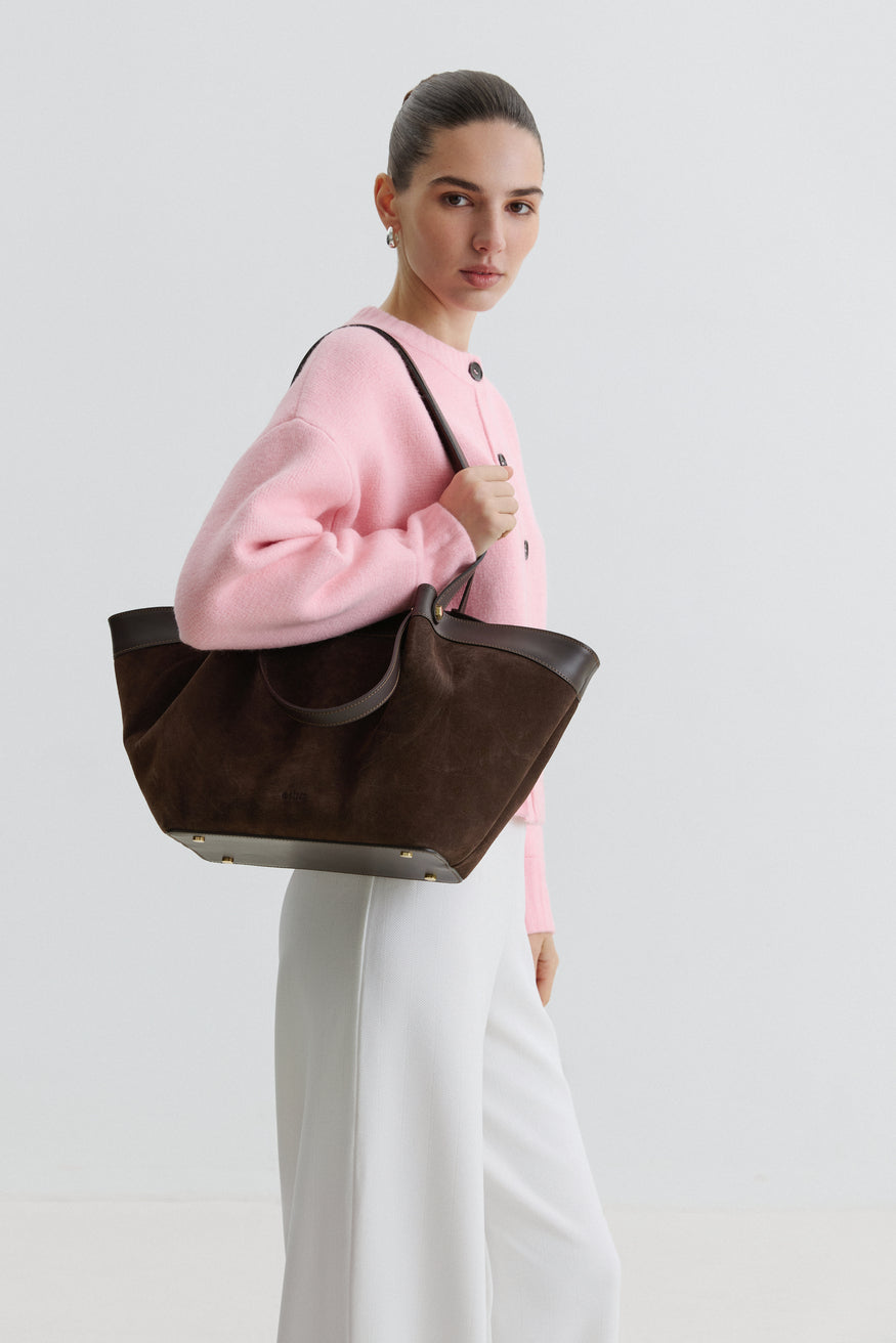 Lifestyle-Aufnahme einer Frau im rosa Pullover, die die dunkelbraune Shopper-Tasche über der Schulter trägt