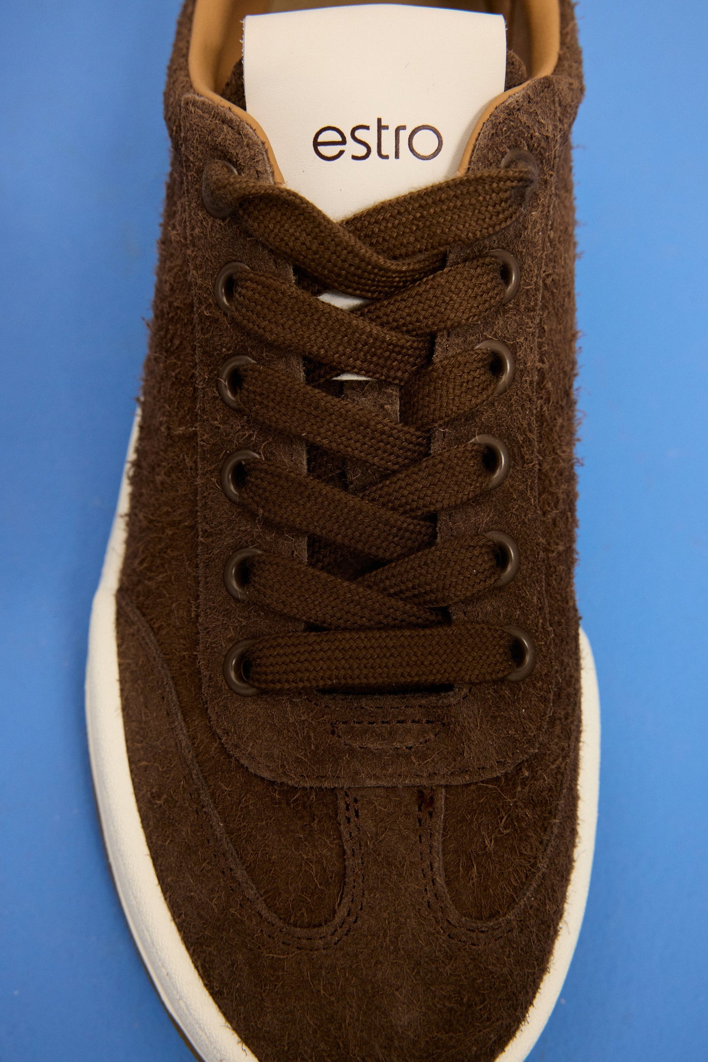Kreative Draufsicht auf den dunkelbraunen Sneaker auf blauem Hintergrund