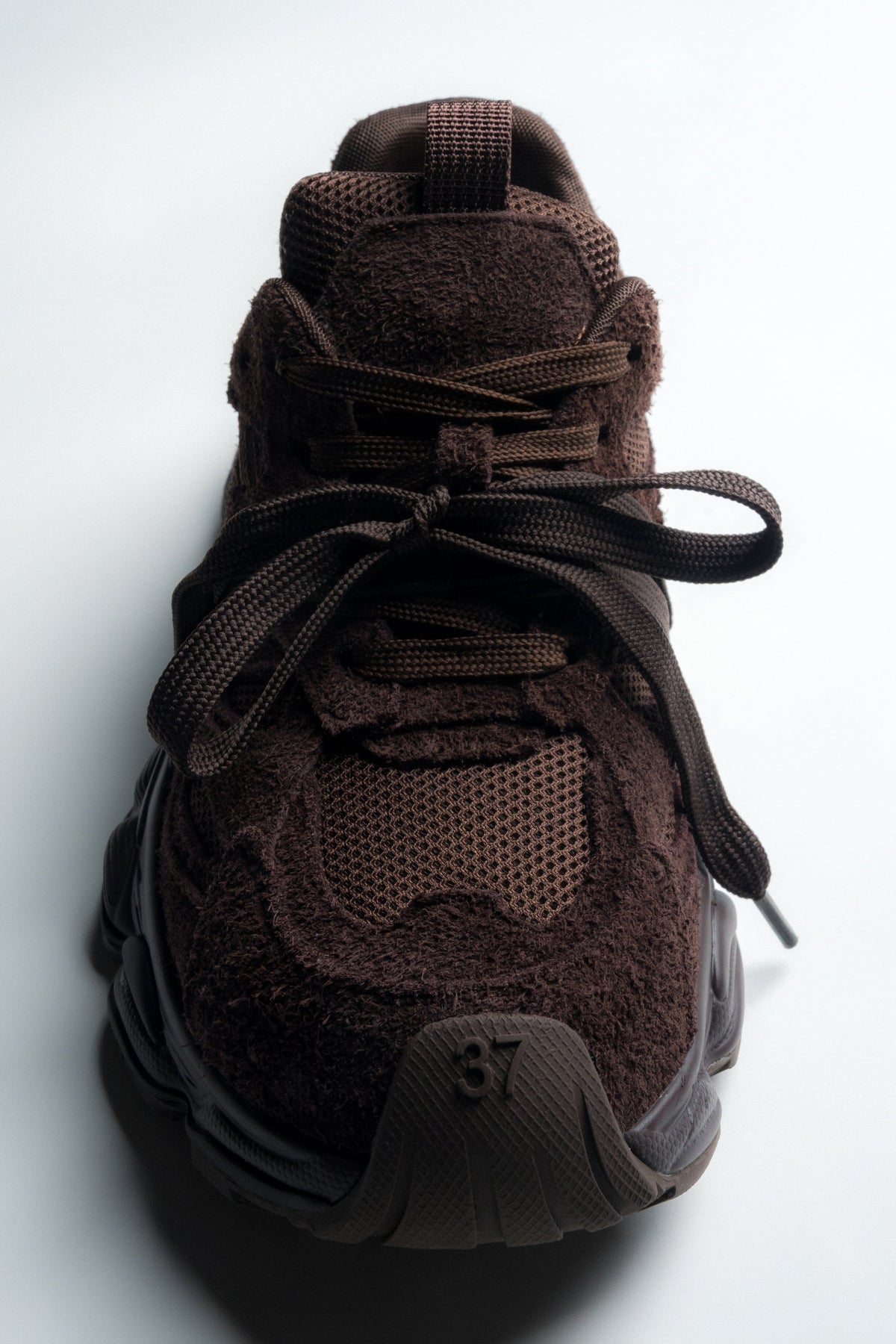 Frontalansicht des dunkelbraunen Sneakers mit Fokus auf die runde Schuhspitze und Textur