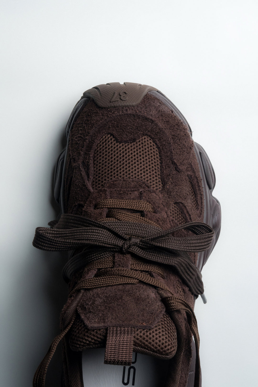 Nahaufnahme der Schnürung und des flauschigen Natur-Velours des braunen Sneakers