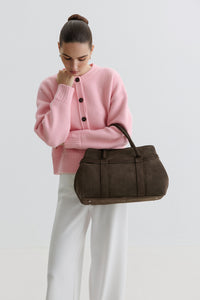 Model in rosa Cardigan und weißer Hose präsentiert die dunkelbraune Tote-Bag