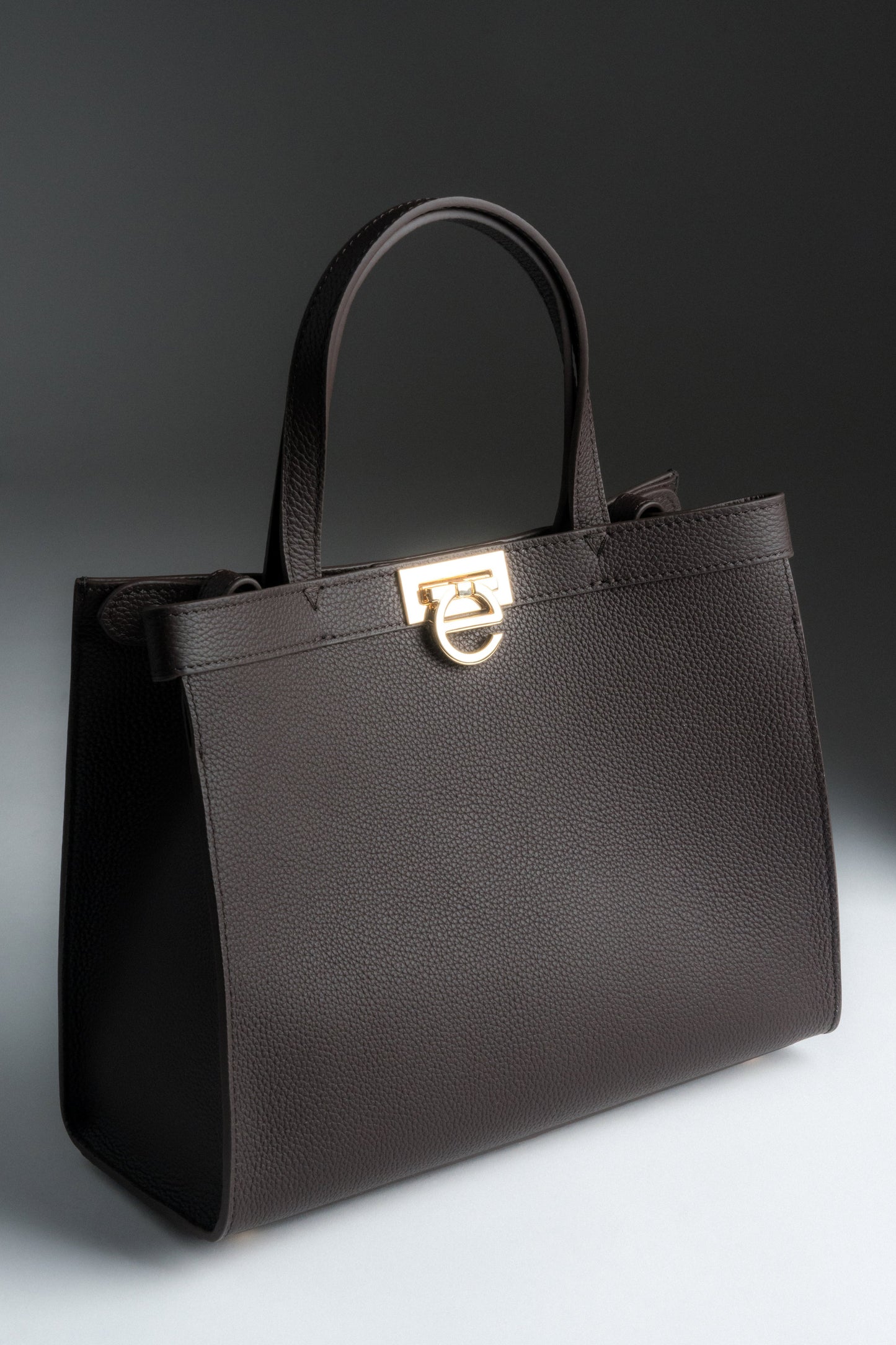 Schräge Frontansicht der dunkelbraunen Damen Tote-Bag aus Naturleder mit goldenem Verschluss.