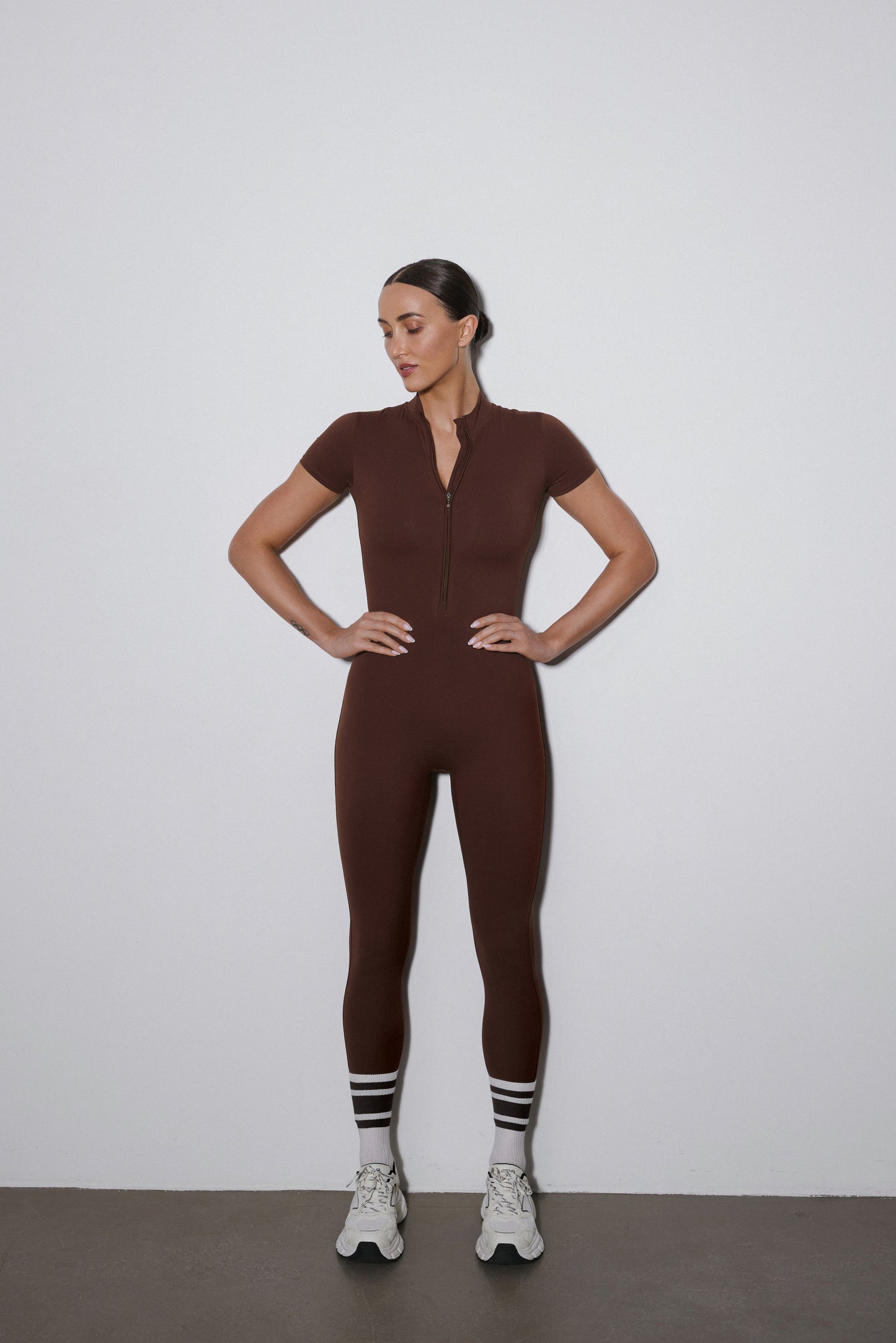 Dunkelbrauner Damen-Sport-Einteiler mit kurzen Ärmeln und langen Beinen in der Vorderansicht.