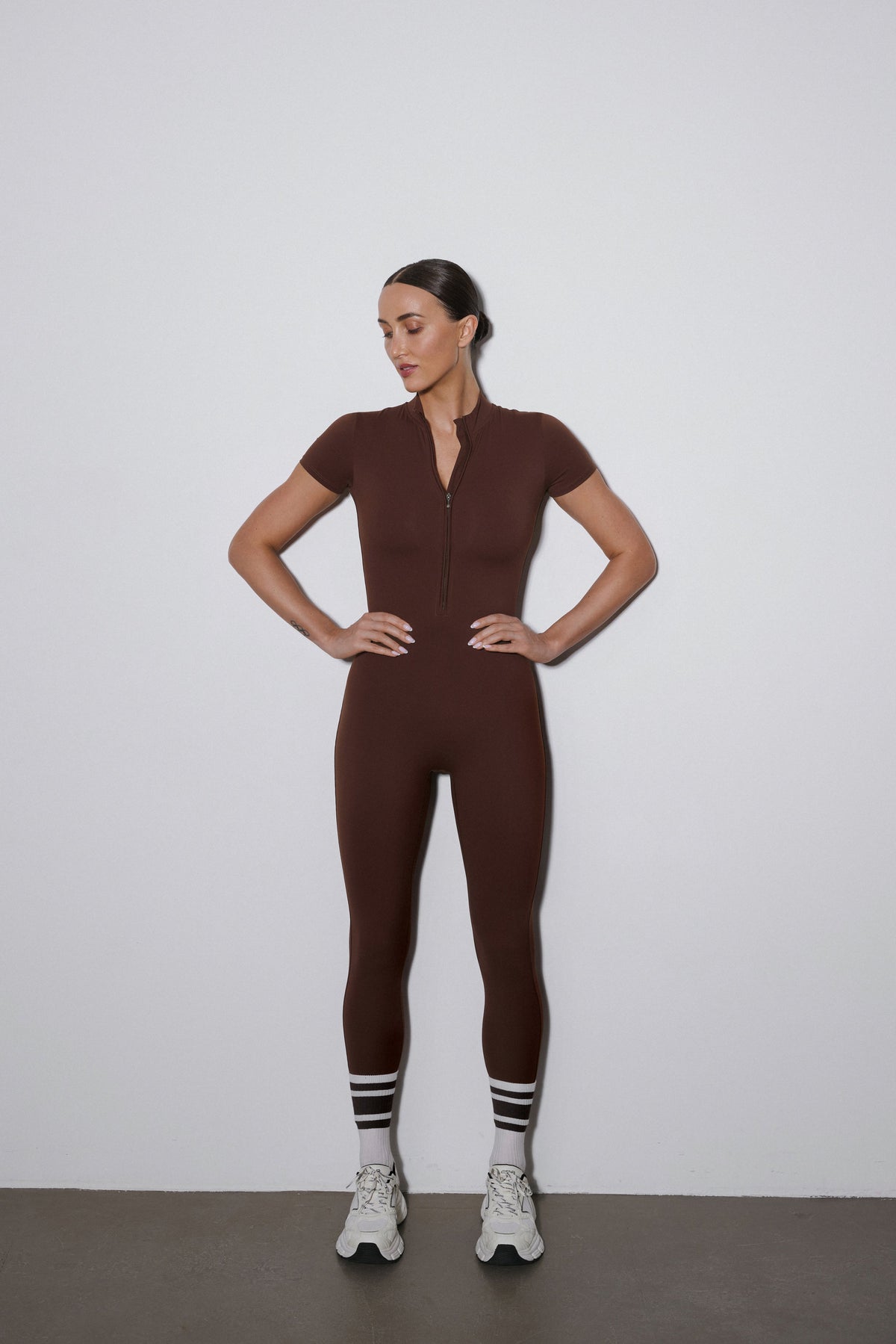 Dunkelbrauner Damen-Sport-Einteiler mit kurzen Ärmeln und langen Beinen in der Vorderansicht.