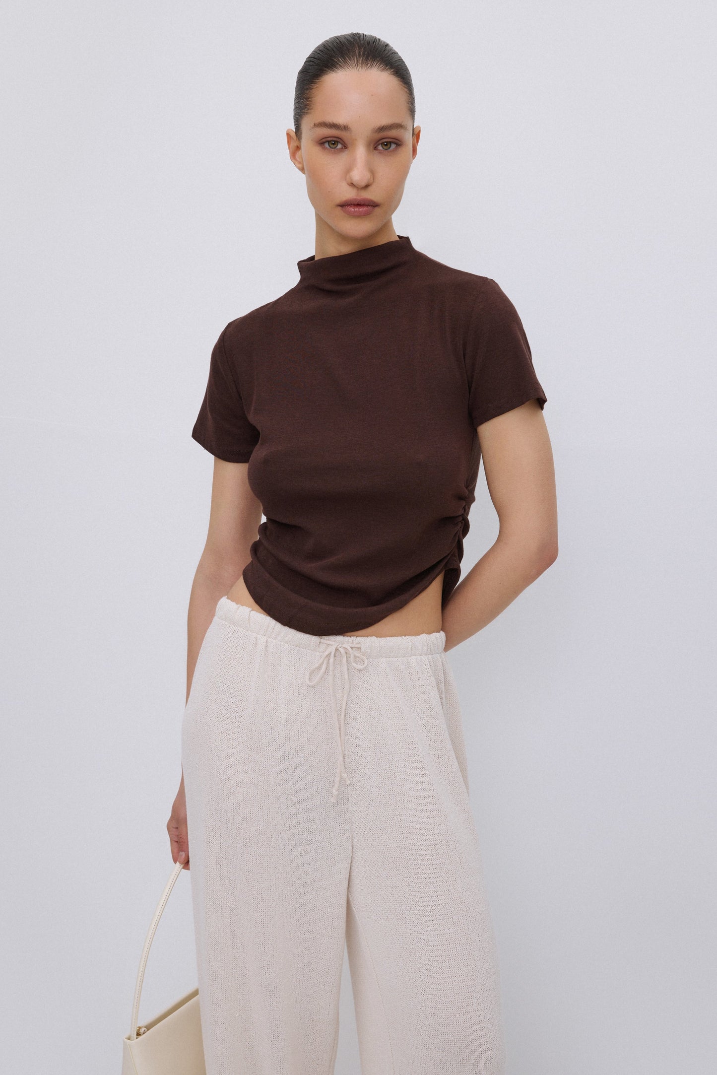 Frontalansicht des dunkelbraunen Damen T-Shirts mit Stehkragen und modischer Taillenraffung.