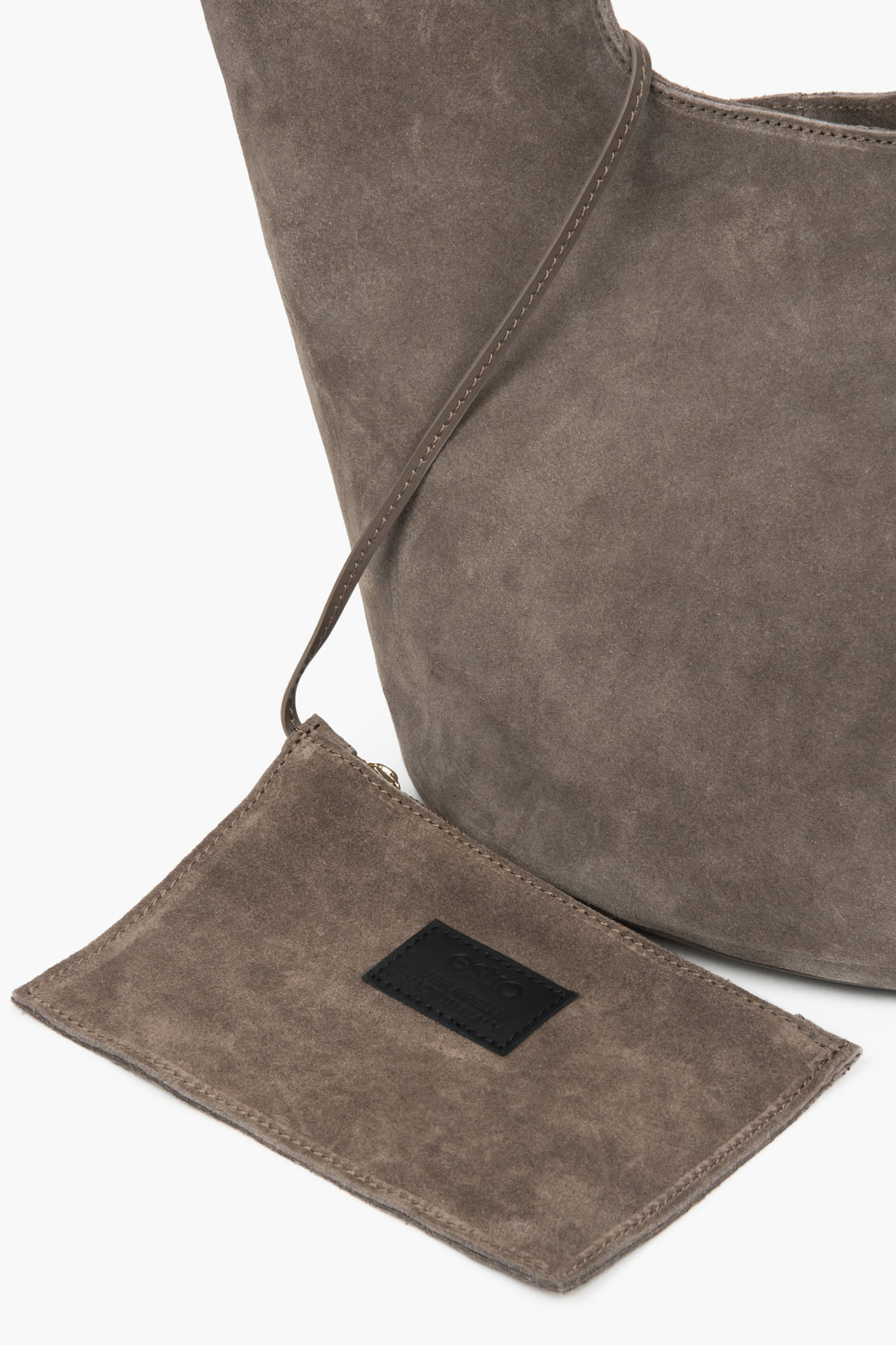 Detailaufnahme der kleinen Reißverschluss-Pochette aus Naturvelours am Befestigungsriemen 