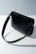 Schräge Ansicht der eleganten schwarzen Damen-Schultertasche aus weichem Echtleder.