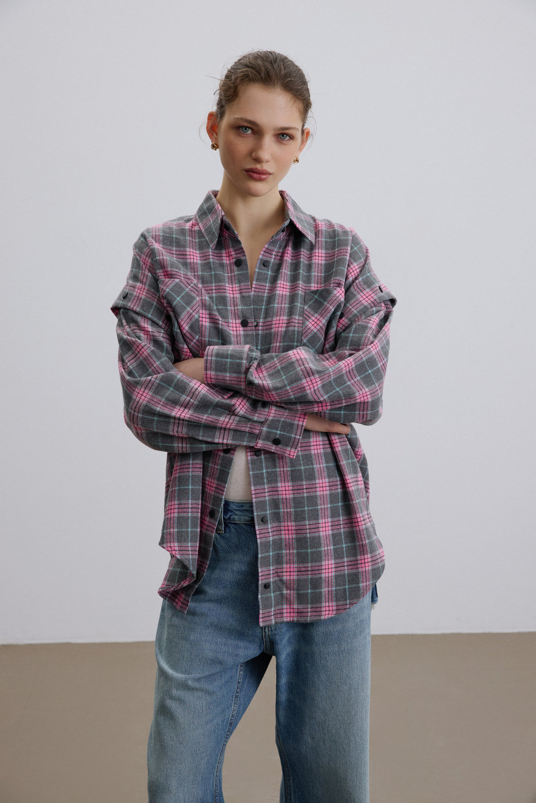 Frau im grau-rosa karierten Oversize-Hemd mit abnehmbaren Ärmeln von Estro.