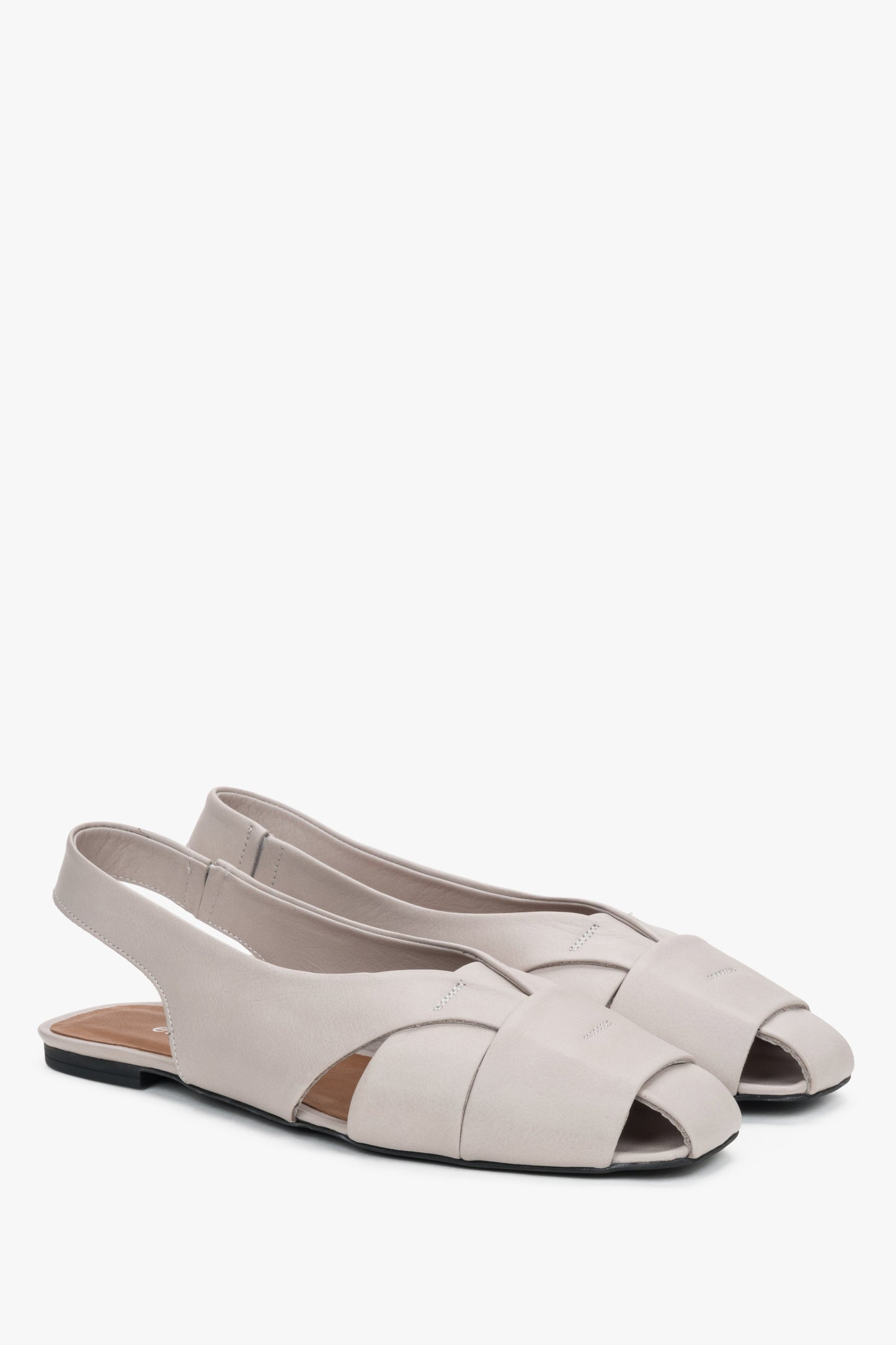 Nahaufnahme der glatten grauen Lederstruktur bei den flachen Sandalen.