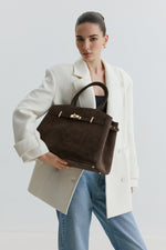 Lifestyle-Aufnahme eines Models mit der eleganten dunkelbraunen Velours-Handtasche