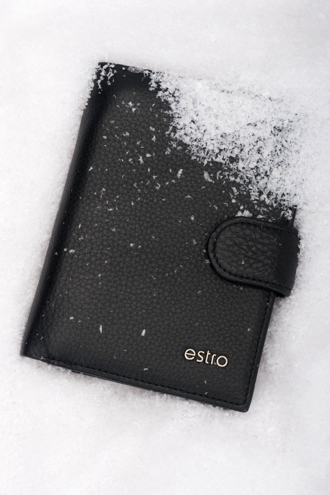 Frontalansicht der handlichen schwarzen Herren-Geldbörse aus Echtleder mit Druckknopfverschluss im Schnee.