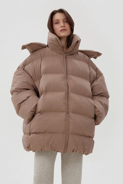 Model präsentiert die offene hellbeige Oversize-Pufferjacke mit hohem Kragen