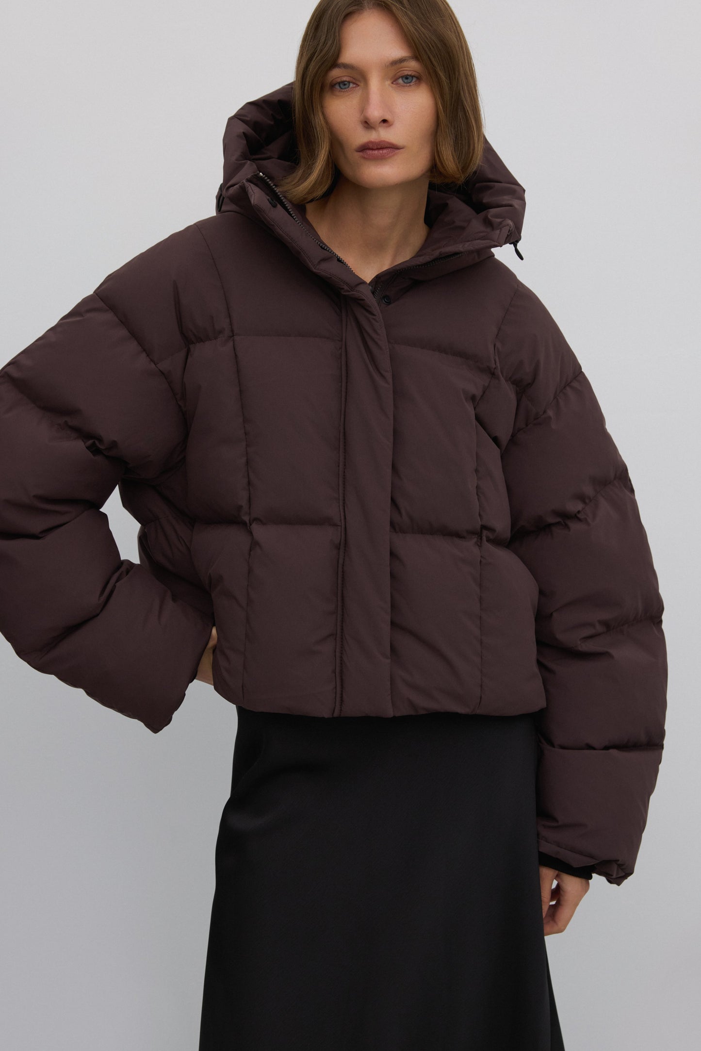 Frontansicht des Models in der dunkelbraunen Oversize-Winterjacke mit hohem Kragen