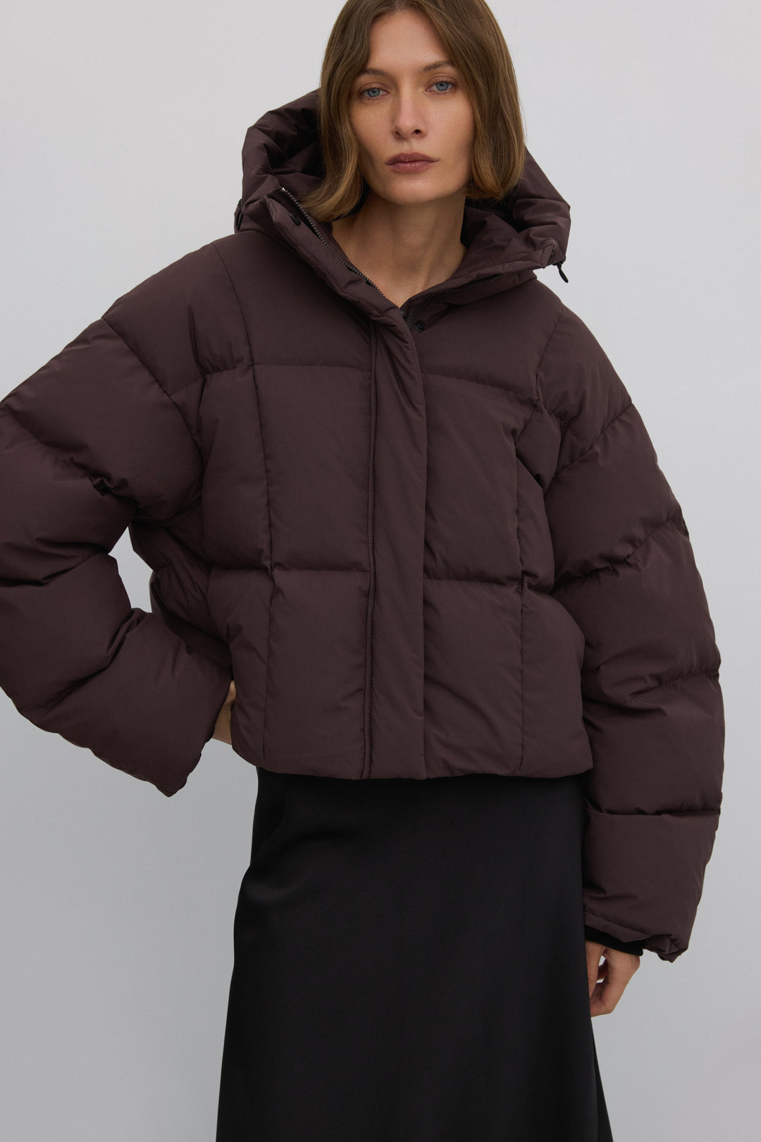 Frontansicht des Models in der dunkelbraunen Oversize-Winterjacke mit hohem Kragen