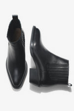 Künstlerische Draufsicht auf das Paar der kurzen schwarzen Cowboystiefel aus Echtleder