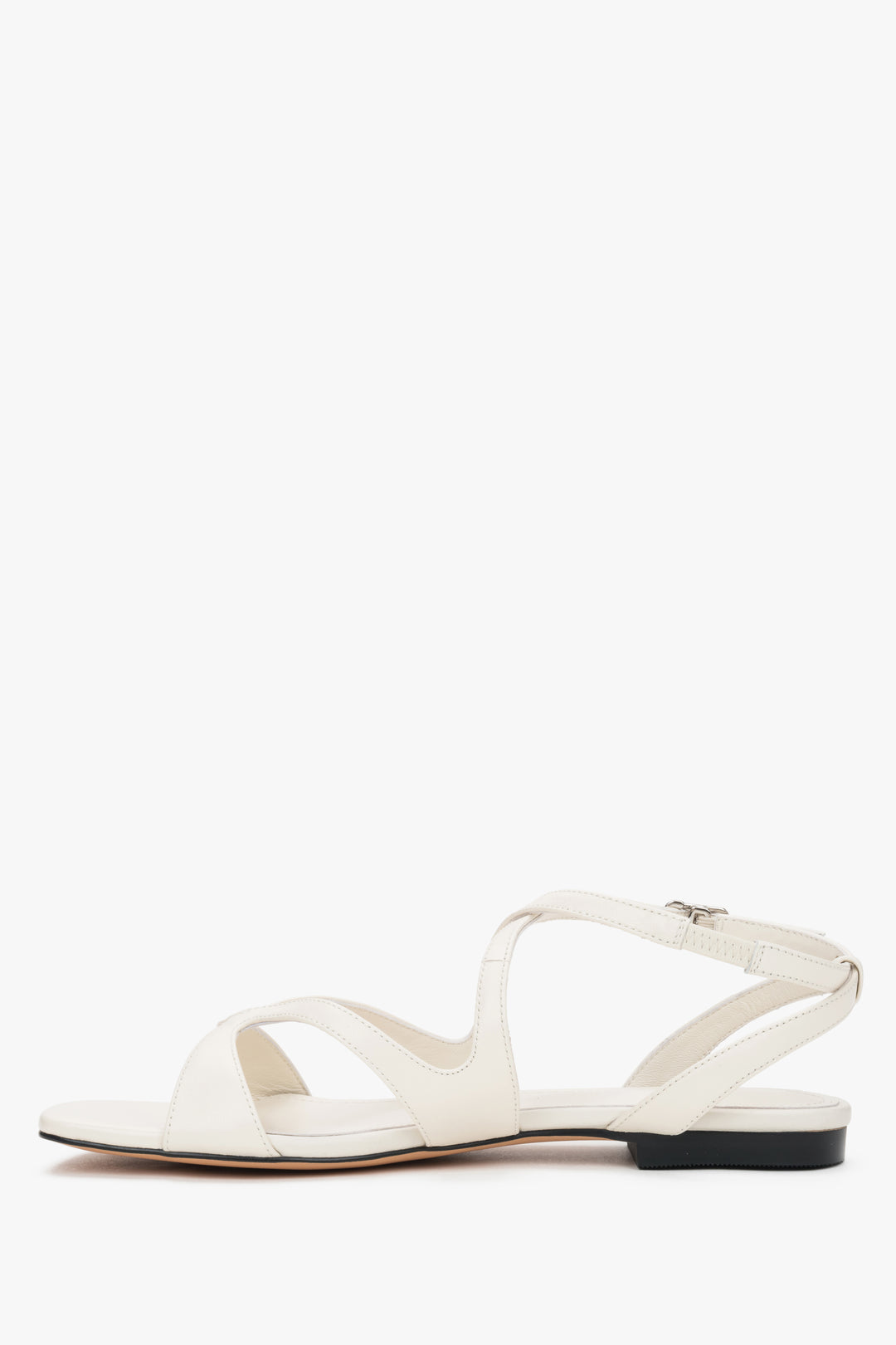 Linkes Seitenprofil der cremefarbenen Sandalen mit gekreuzten Riemen.