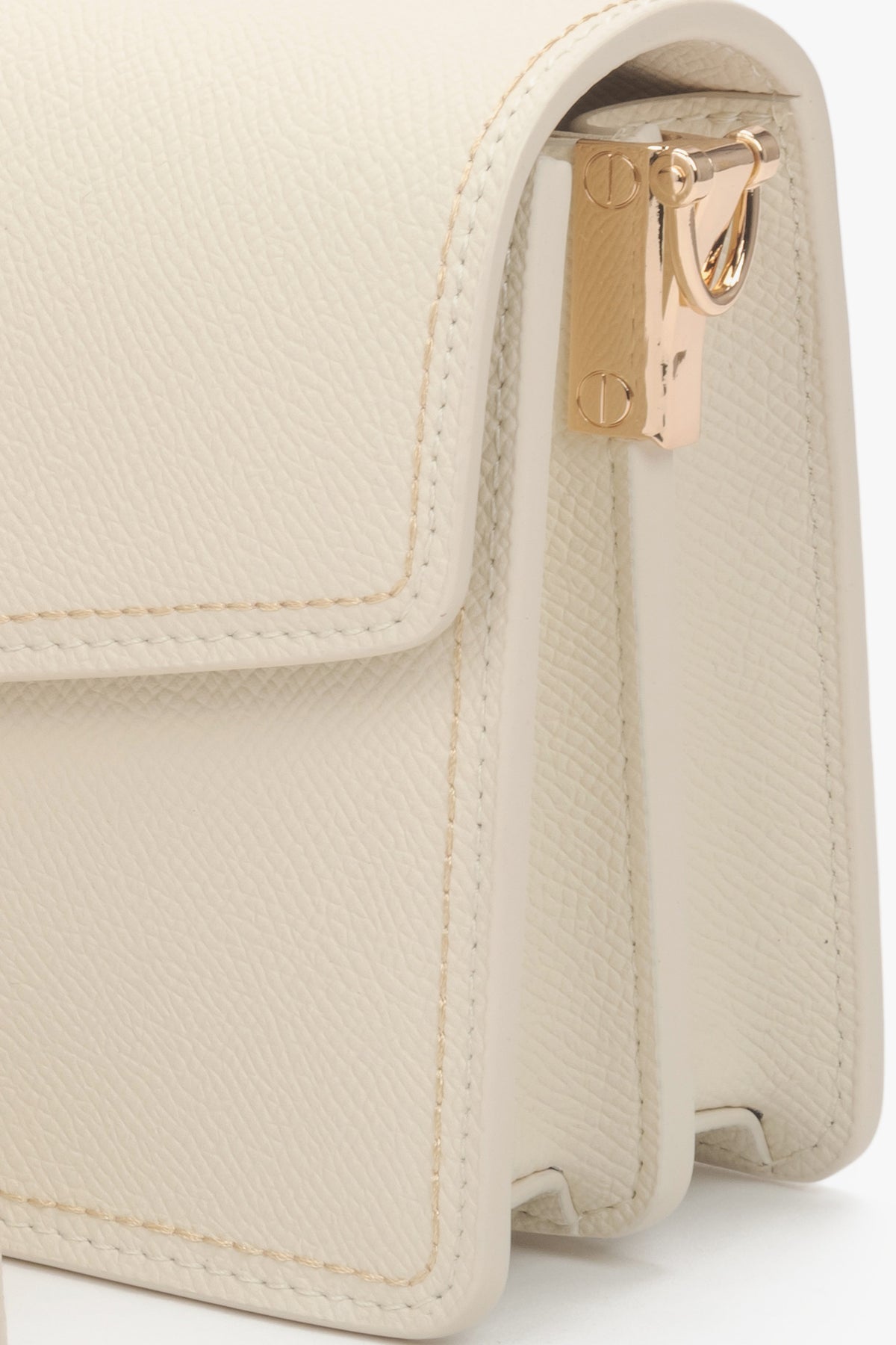 Detailaufnahme der goldenen Beschläge an der hellbeigen Ledertasche.