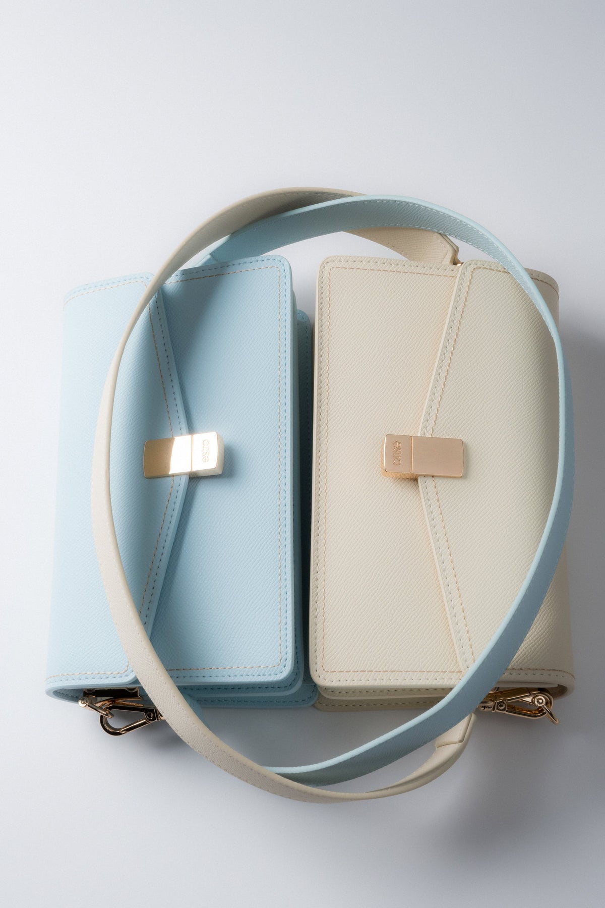 Draufsicht auf die milchbeigen und hellblauen Ledertaschen mit Trageriemen.