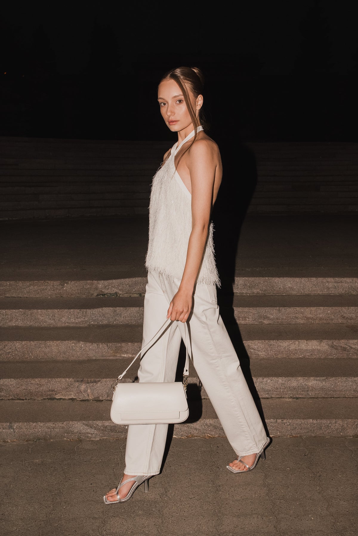 Dynamische Lifestyle-Aufnahme des Models auf einer abendlichen Steintreppe mit der Messenger-Bag