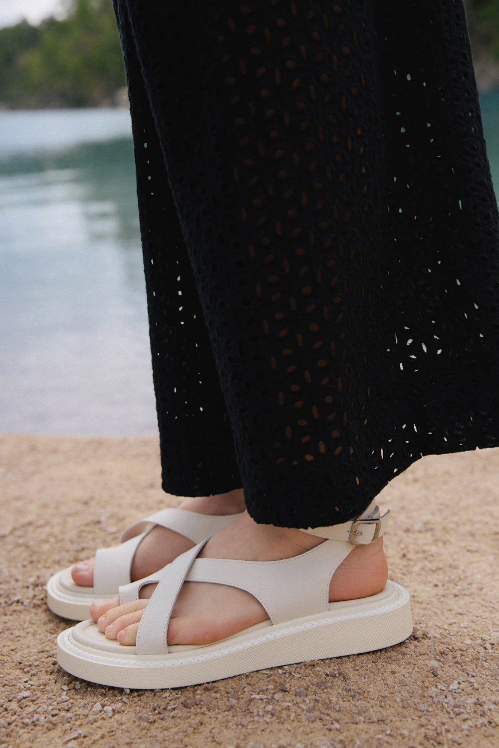 Lifestyle-Ansicht der milchweißen Damen-Sandalen mit Plateausohle am Wasser.