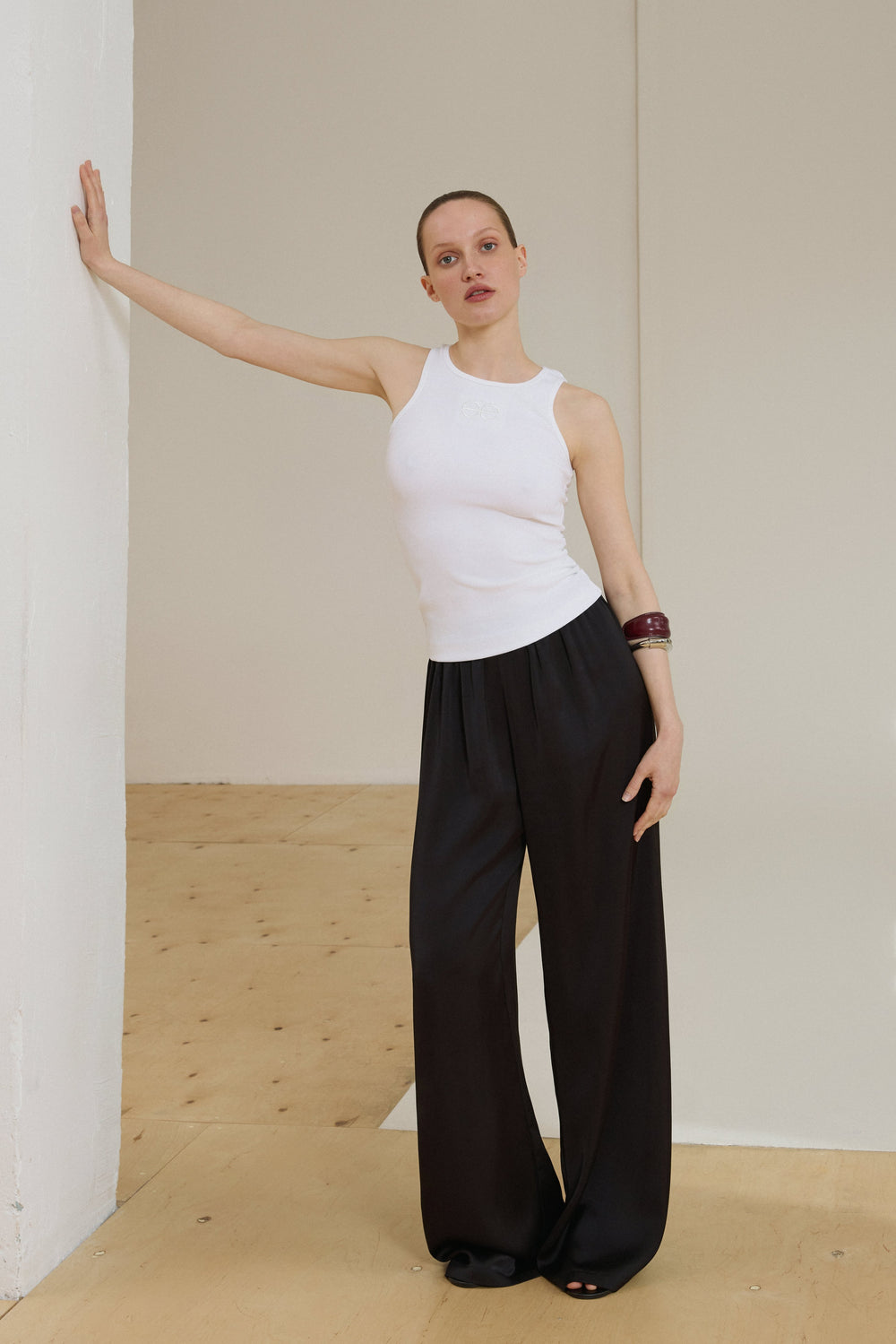 Model in milchweißem ärmellosem Top und schwarzer weiter Hose