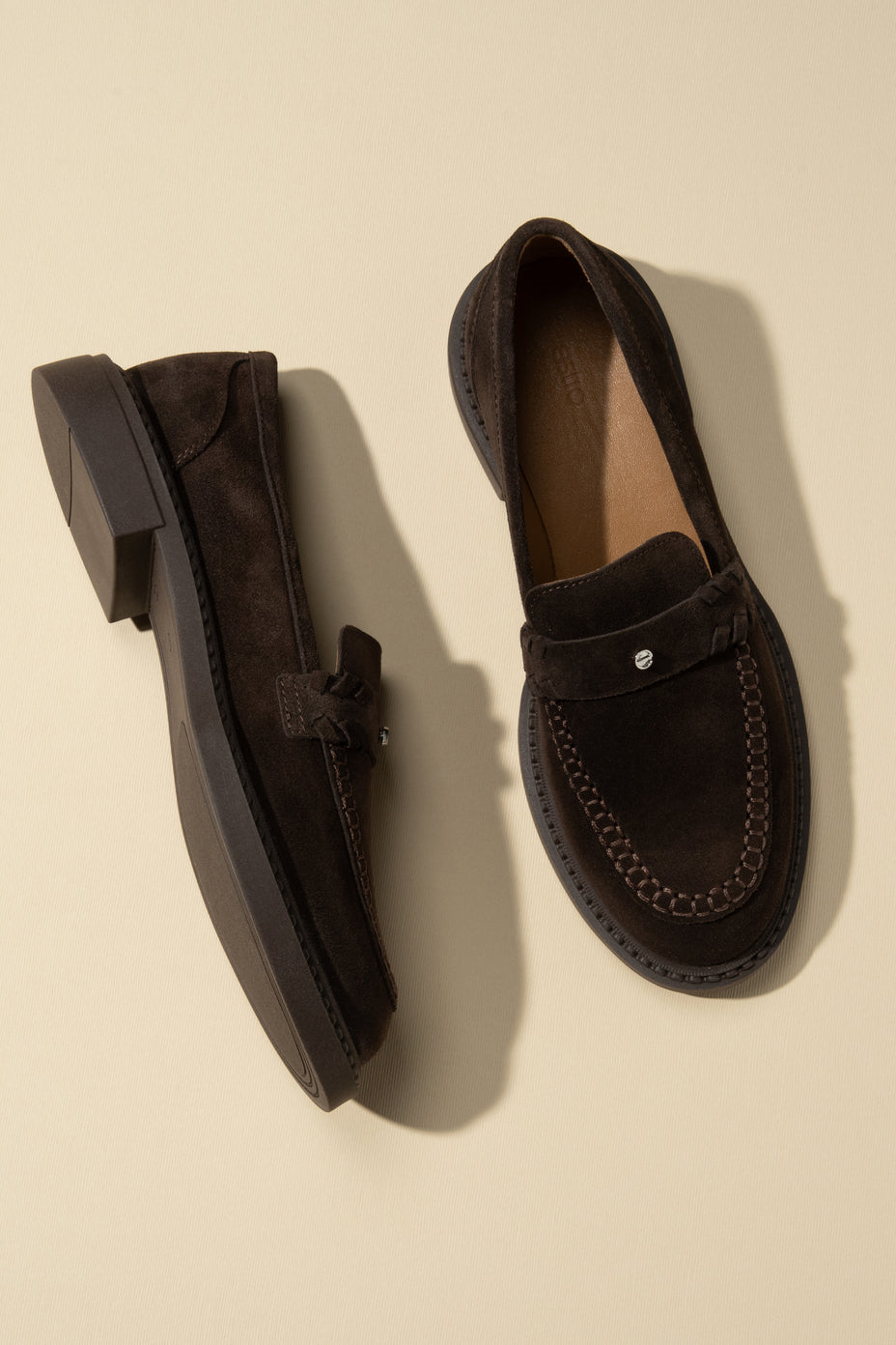 Draufsicht auf das Paar dunkelbrauner Penny-Loafer aus Velours in edlem Setting