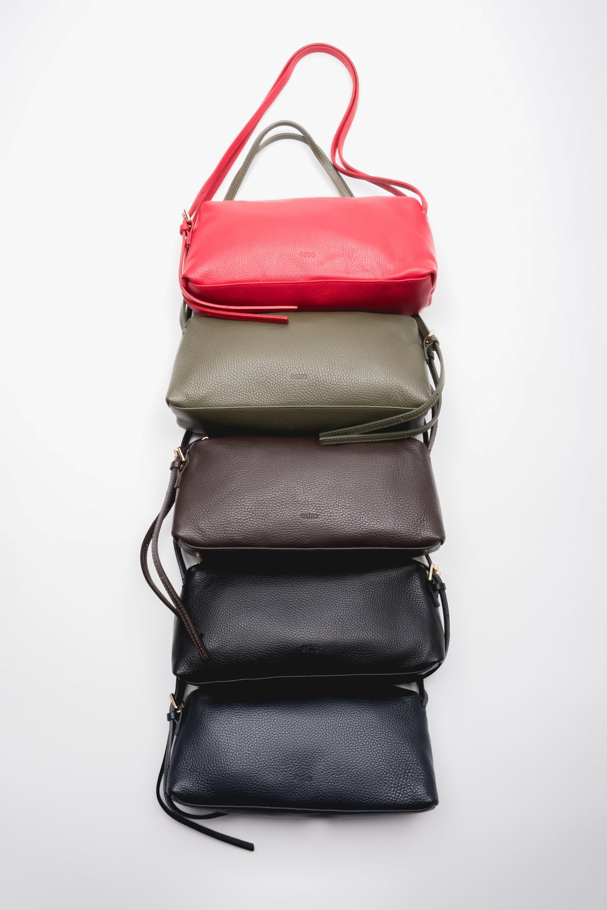 Gestapelte Präsentation der länglichen Leder Schultertaschen in den Farben Rot, Oliv, Braun und Schwarz