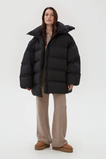 Frontale Ansicht der schwarzen Oversize-Pufferjacke an der Model