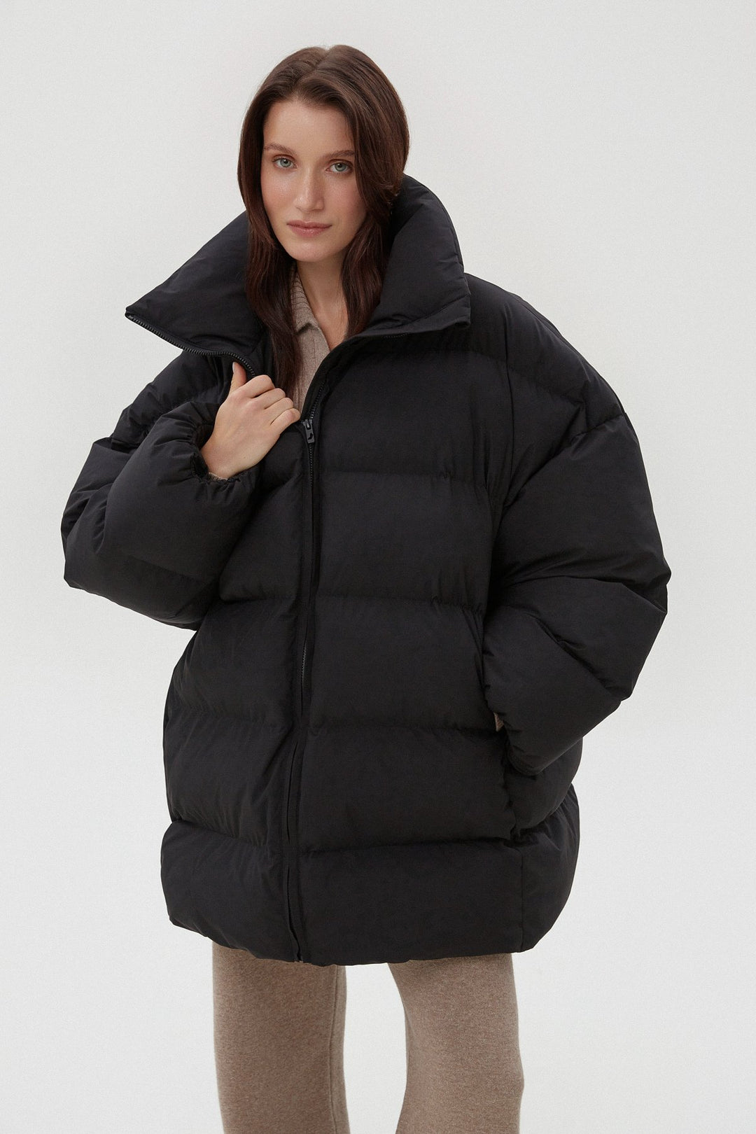 Nahaufnahme des Models in der schwarzen Pufferjacke mit Fokus auf den hohen Kragen und den Reißverschluss 