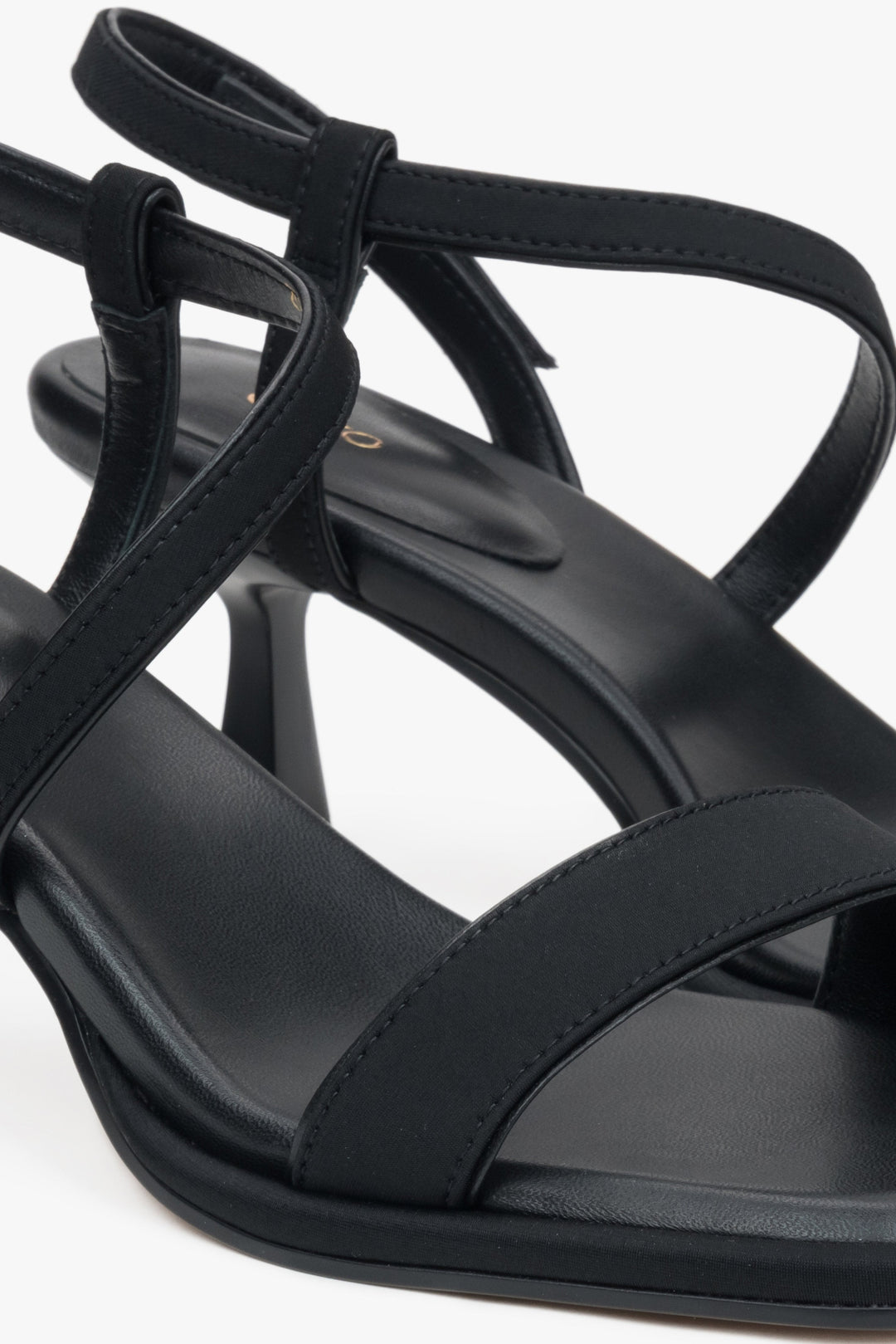 Nahaufnahme der feinen Textil-Riemchen und der weichen Echtleder-Innensohle der schwarzen Damen-Sandalen.