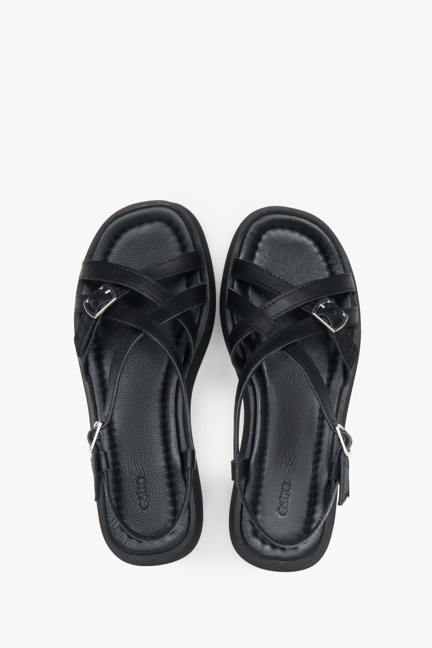 Draufsicht auf das Echtleder-Fußbett und die überkreuzten Riemen der schwarzen Sandalen