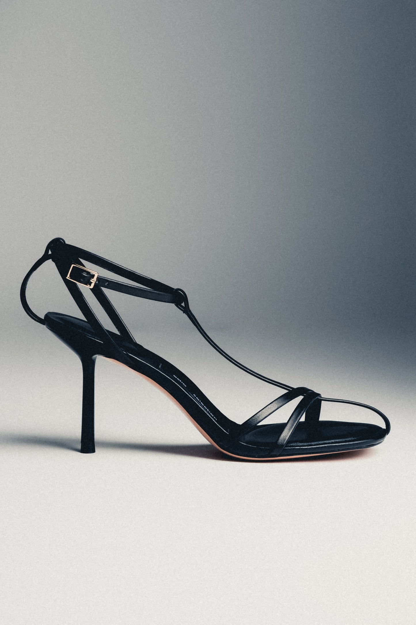 Schwarze Damen-Sandalette aus Echtleder in schräger Ansicht auf grauem Hintergrund