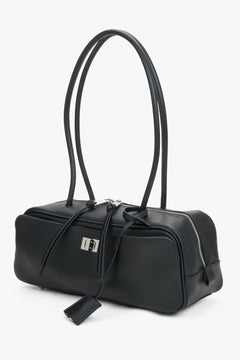 Schräge Ansicht der eleganten Tasche mit Zieranhänger und Zugbändern am Reißverschluss.