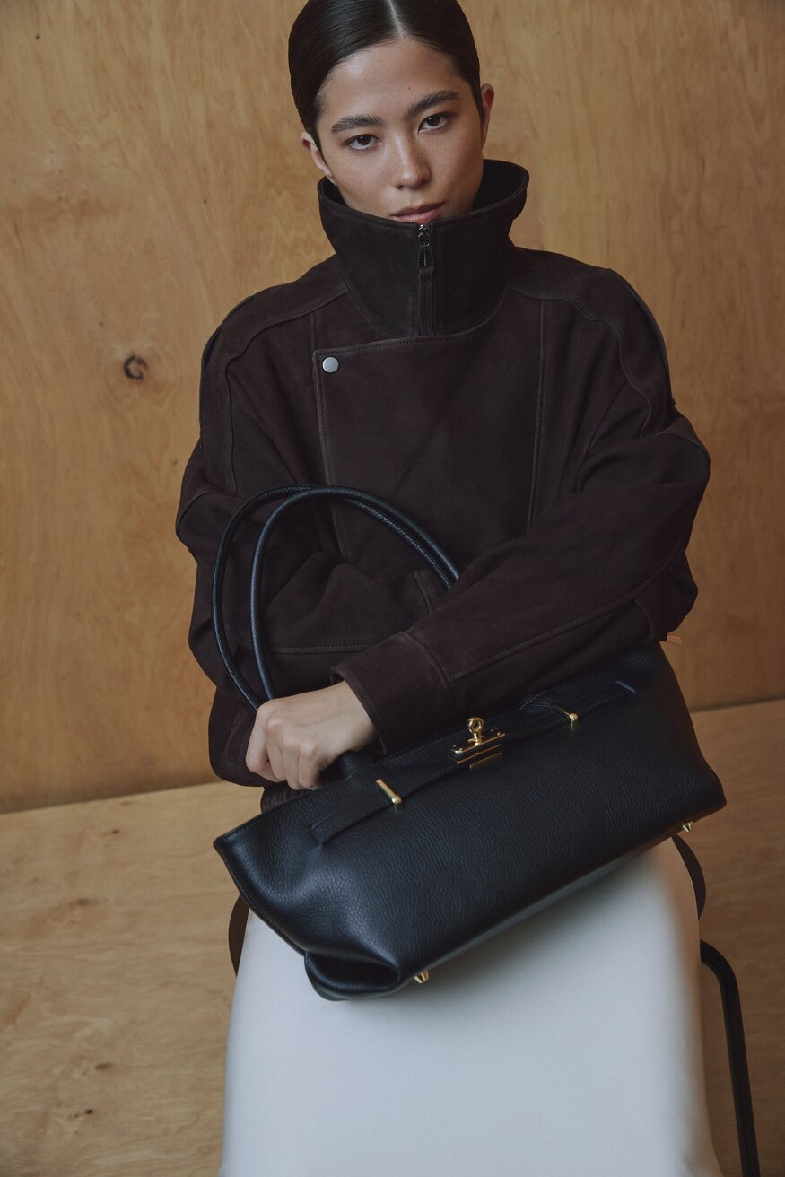 Kampagnenbild eines Models, das die schwarze Ledertasche elegant über der Schulter trägt