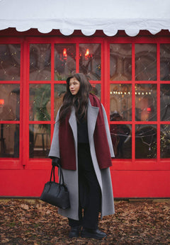Lifestyle-Aufnahme einer Frau im Herbstmantel, die die schwarze Schultertasche in der Hand trägt